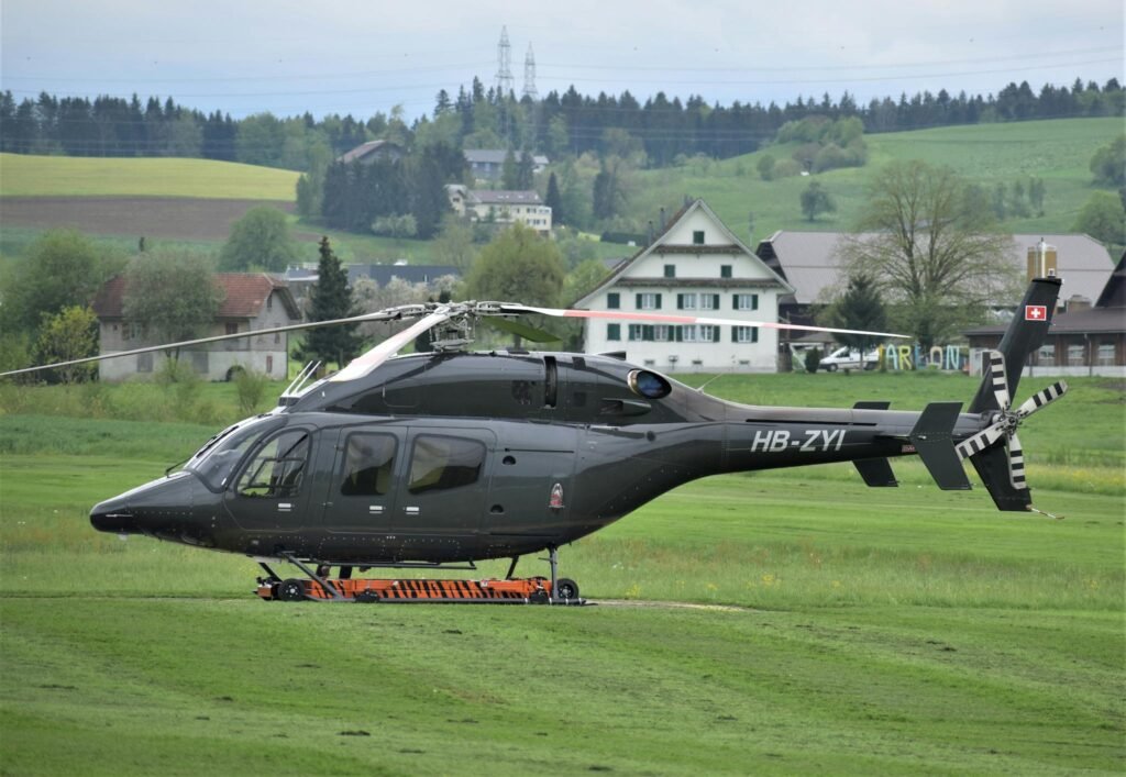 A sleek helicopter parked on a scenic airfield in Beromünster, Switzerland.
